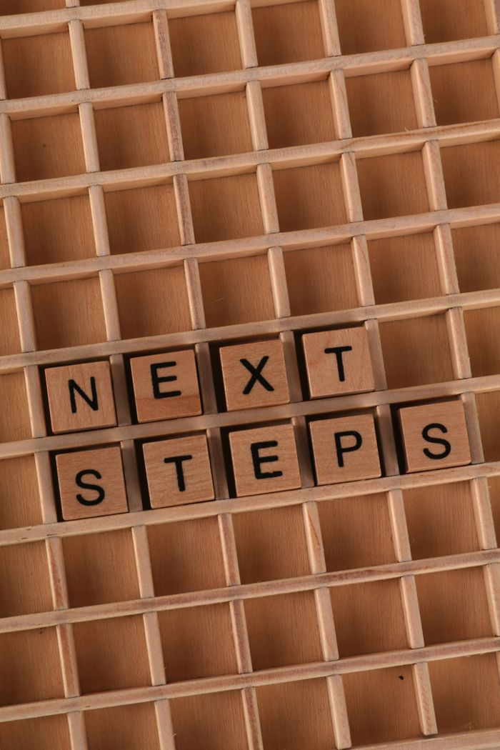 gallery-6 Wooden cubes arranged on a grid showing the words 'Next Steps' for motivational concept.
